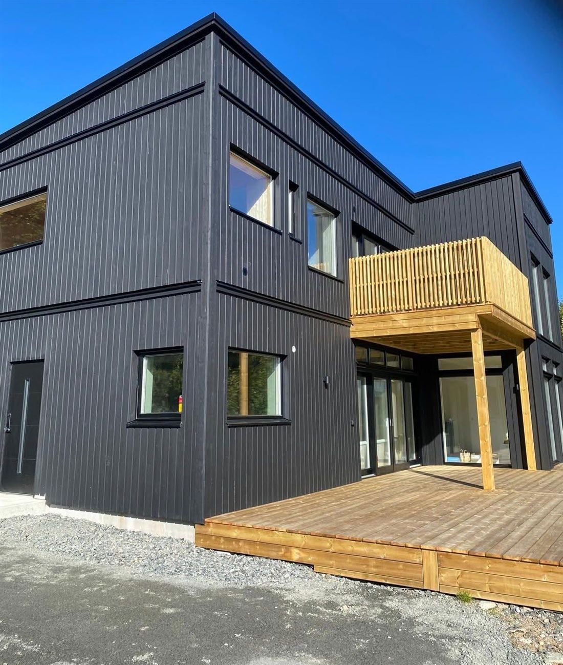 Black timber-clad house with a balcony and deck